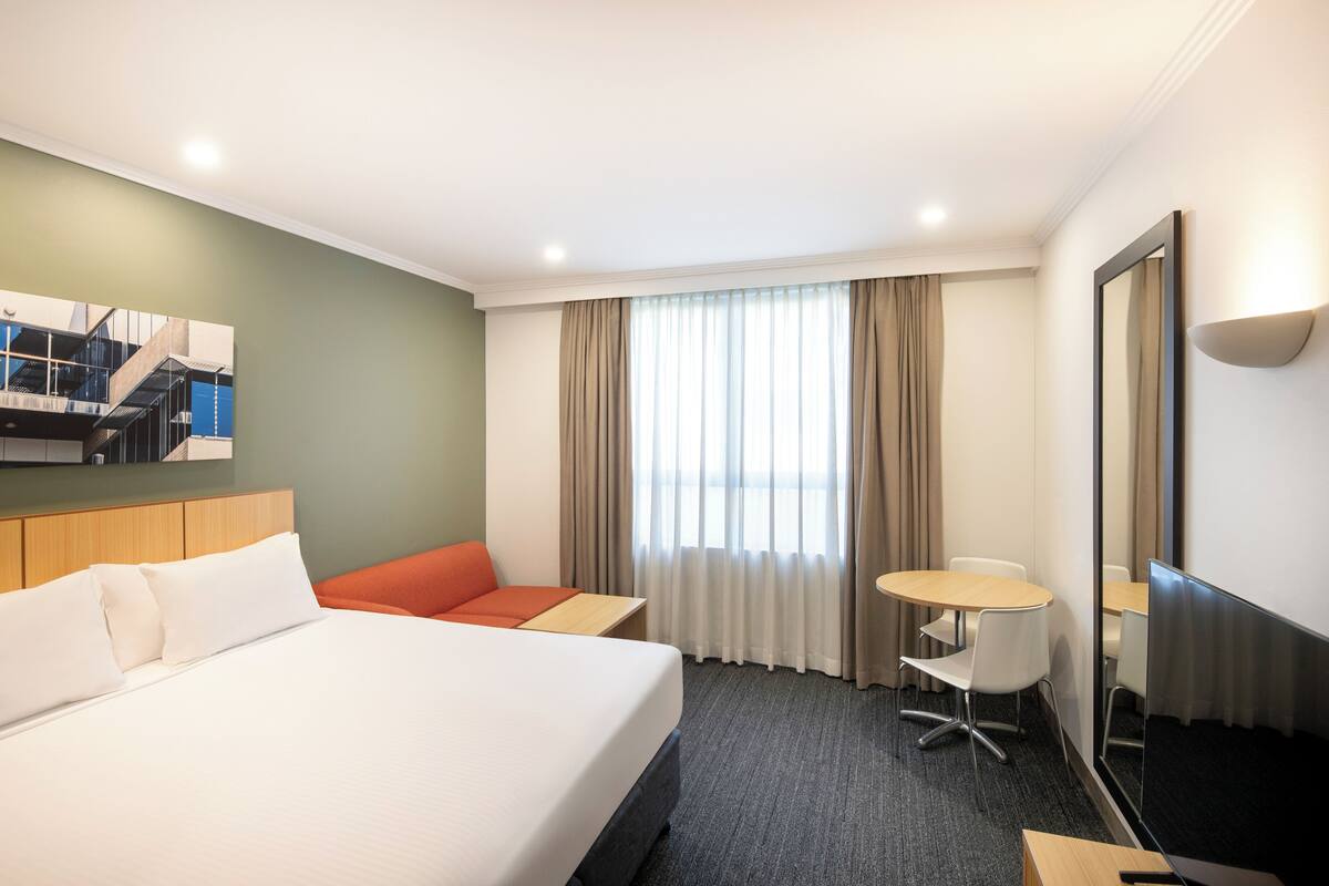 Ein Hotelzimmer mit einem Bett, einer Sitzecke, einem kleinen Tisch und einem großen Spiegel.