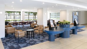 A modern lobby with seating areas, a reception desk, and large windows.