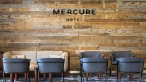A reception area with a wooden wall, a sofa, and four armchairs.