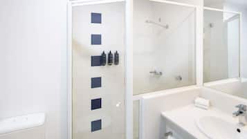 Un baño moderno con ducha envuelta en vidrio, un lavabo blanco y un espejo grande.