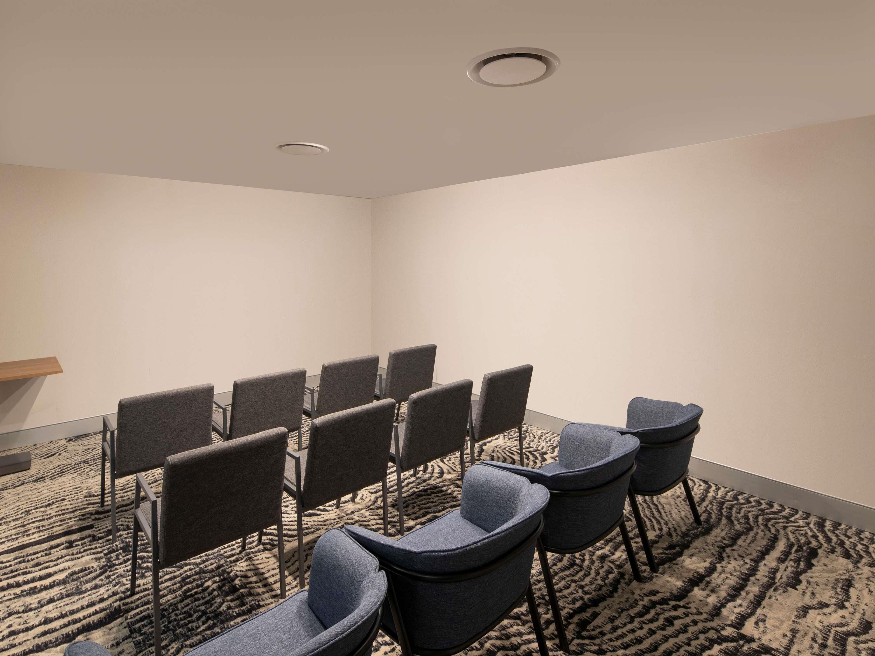A conference room with rows of chairs, a carpeted floor, and a ceiling light.