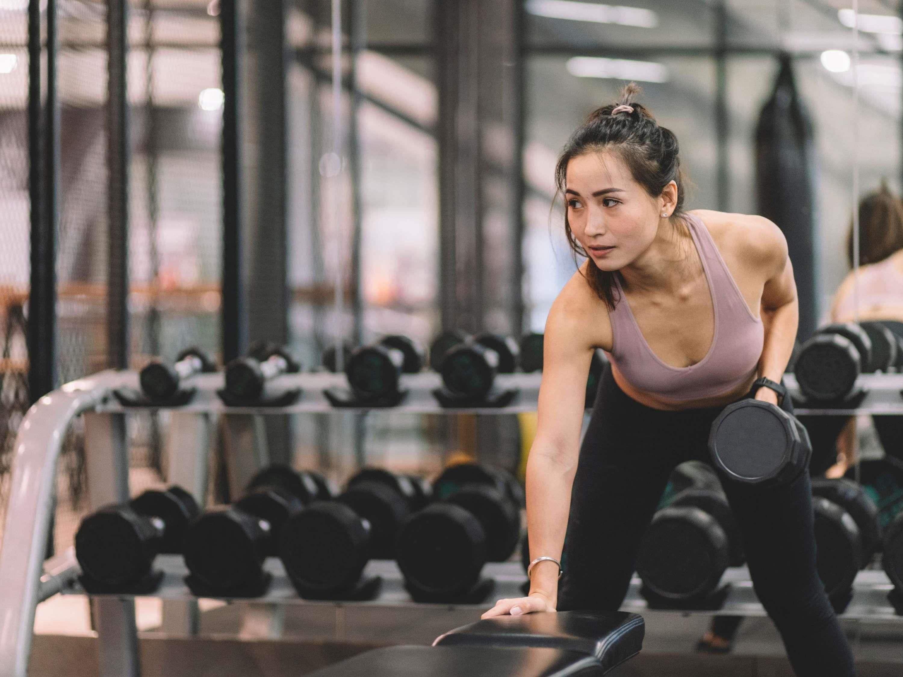 Un gimnasio con una persona haciendo una plancha, rodeada de pesas.