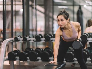 A gym with a person doing a plank exercise, surrounded by dumbbells. - The Sebel Sydney Martin Place (Sydney)