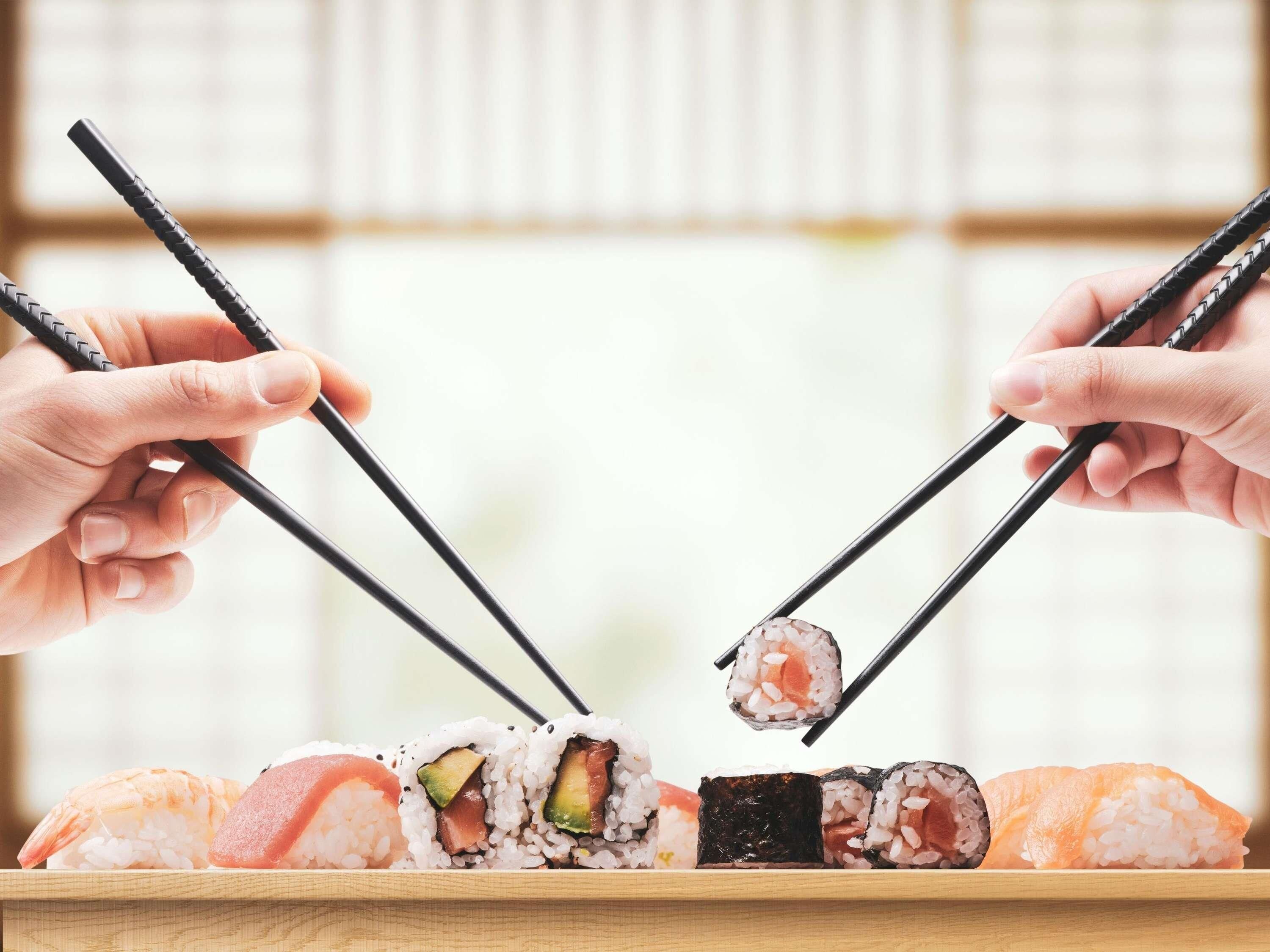Ein aus Holz gefertigtes Sushi-Tablett mit verschiedenen Sushi-Sorten und Stäbchen.
