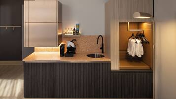 A modern kitchen with a built-in sink, a coffee machine, and a shelf with bottles.