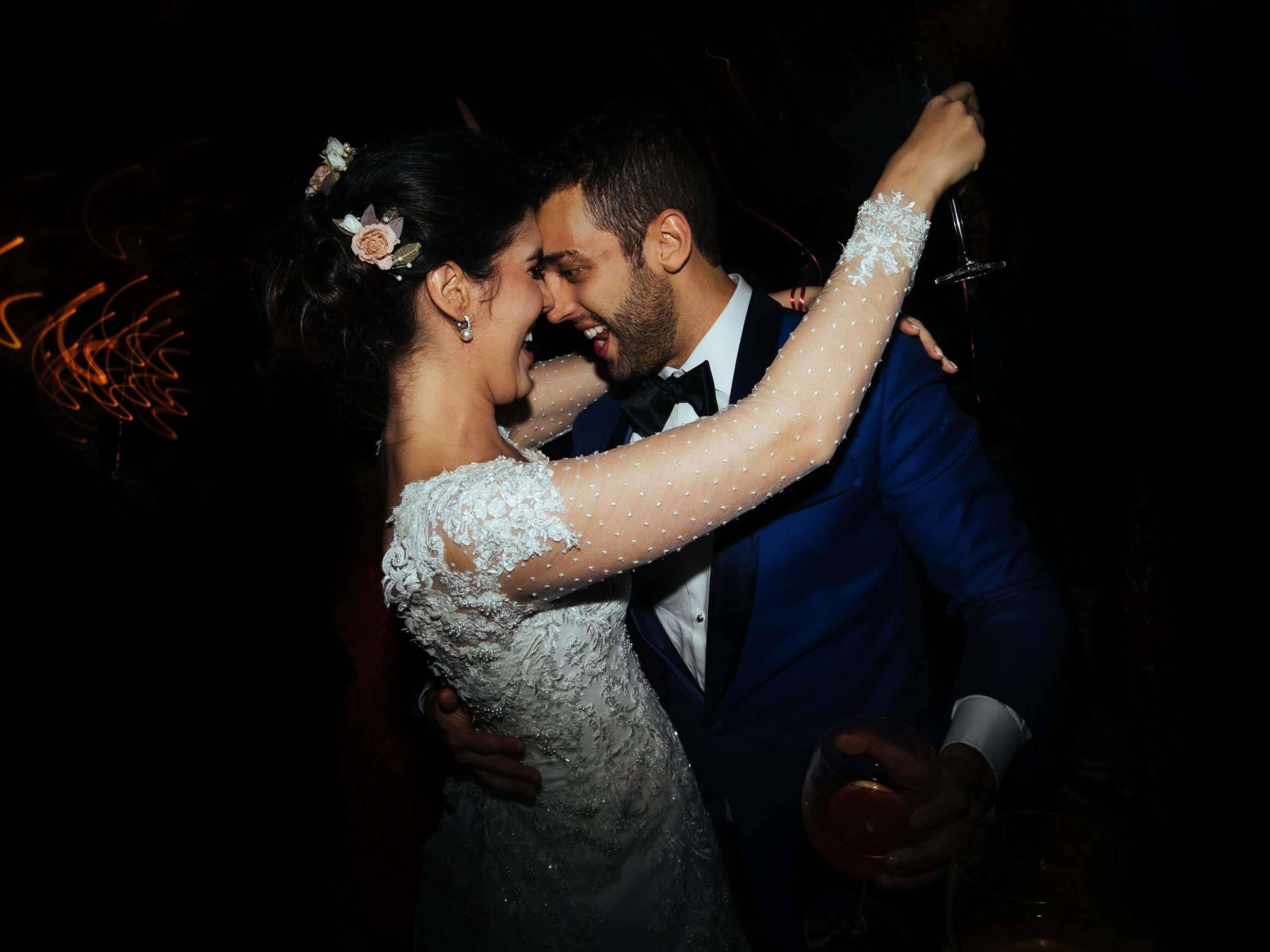 Una pareja bailando, una vestida de blanco y el otro con traje azul.