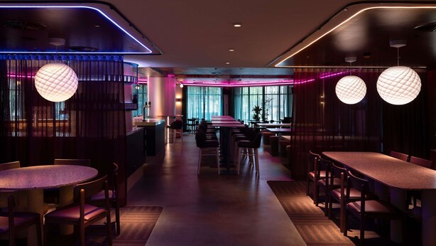 A modern restaurant with round tables, ambient lighting, and a central walkway. - ibis Styles Sydney Central (Sydney)