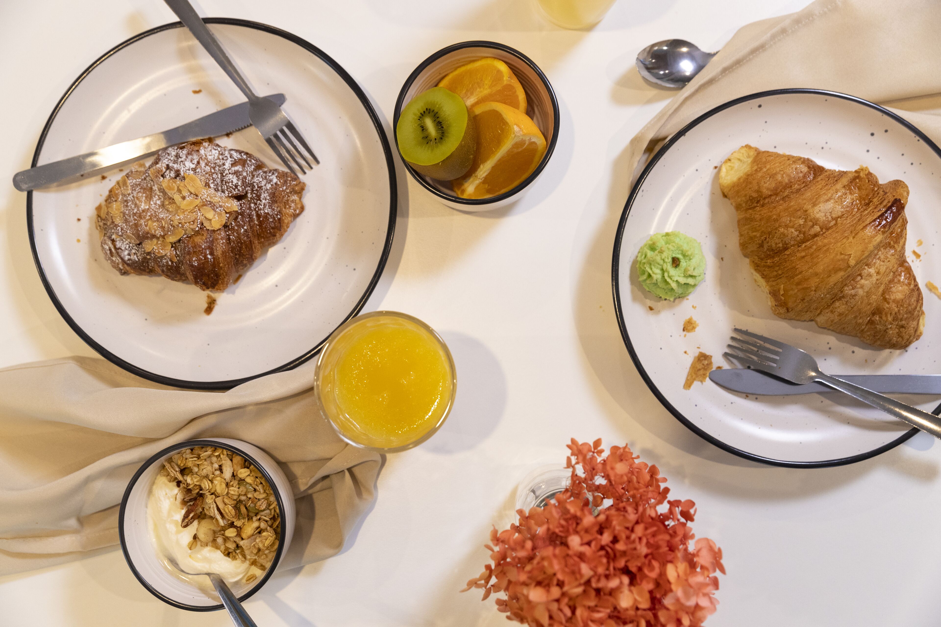 Desayuno con platos de comida, un vaso de jugo de naranja y un tazón de yogur.