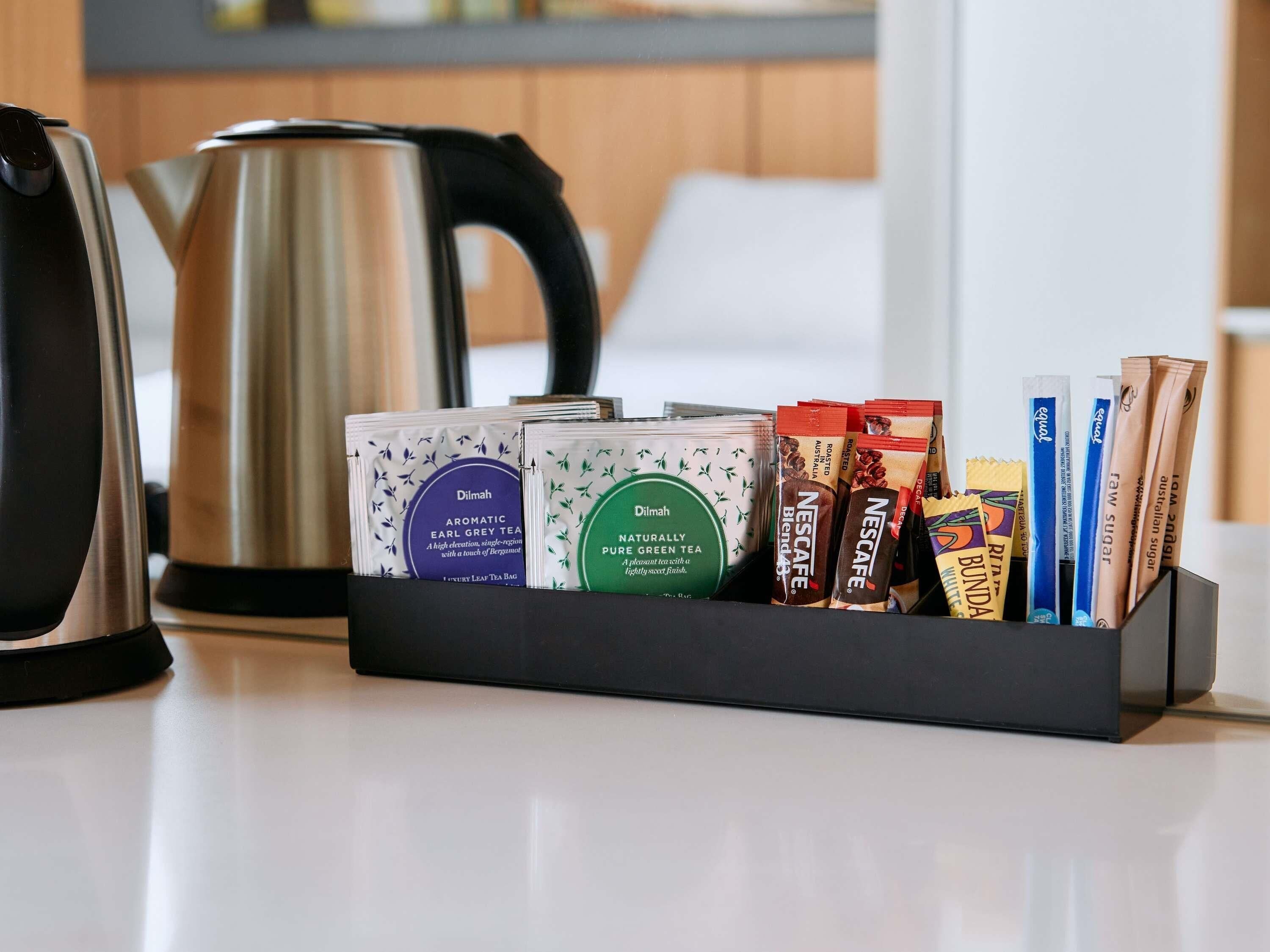 A tea station with various tea bags and a kettle on a countertop.