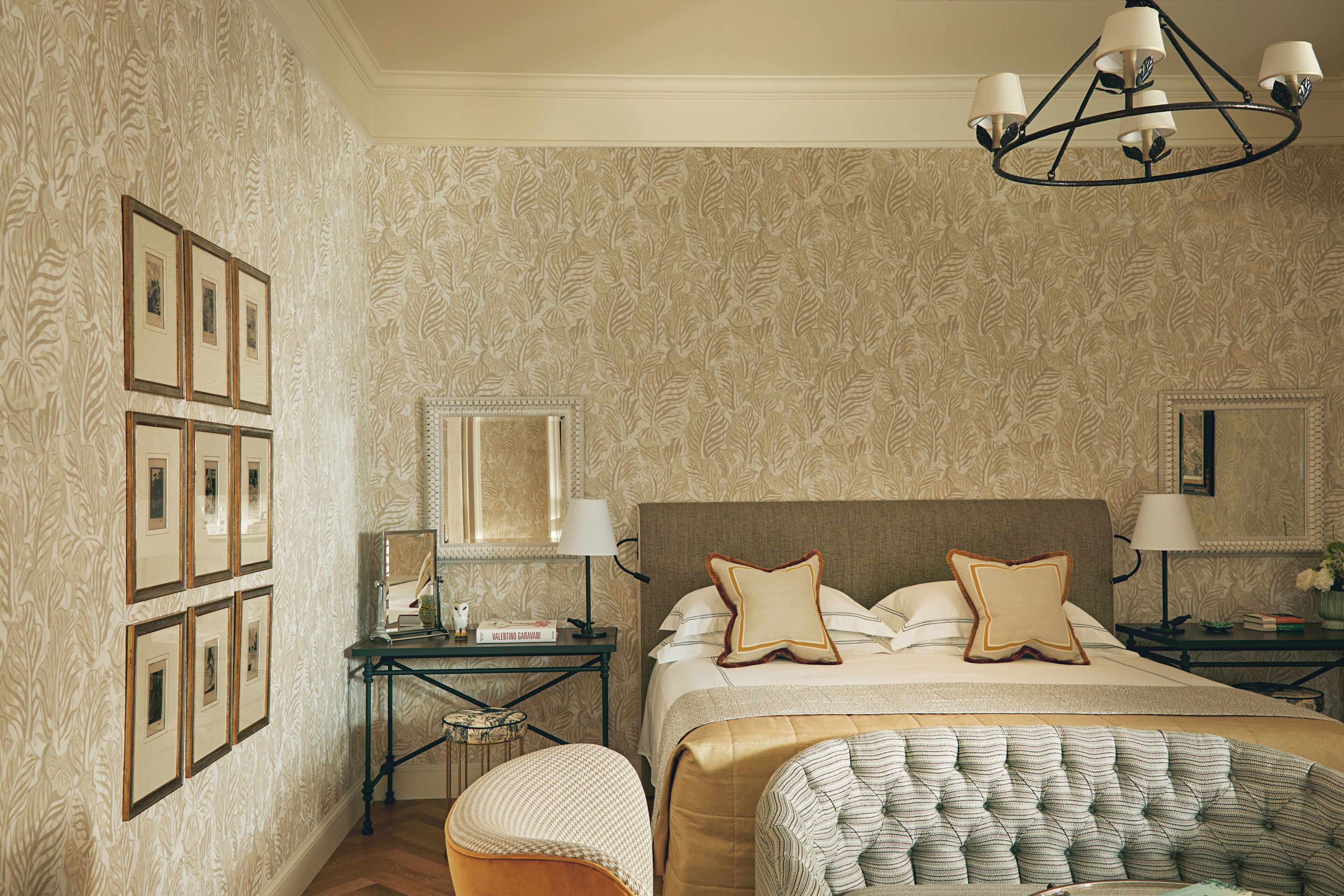Una camera da letto con un letto grande, due comodini, uno specchio, quadri appesi al muro e un lampadario.