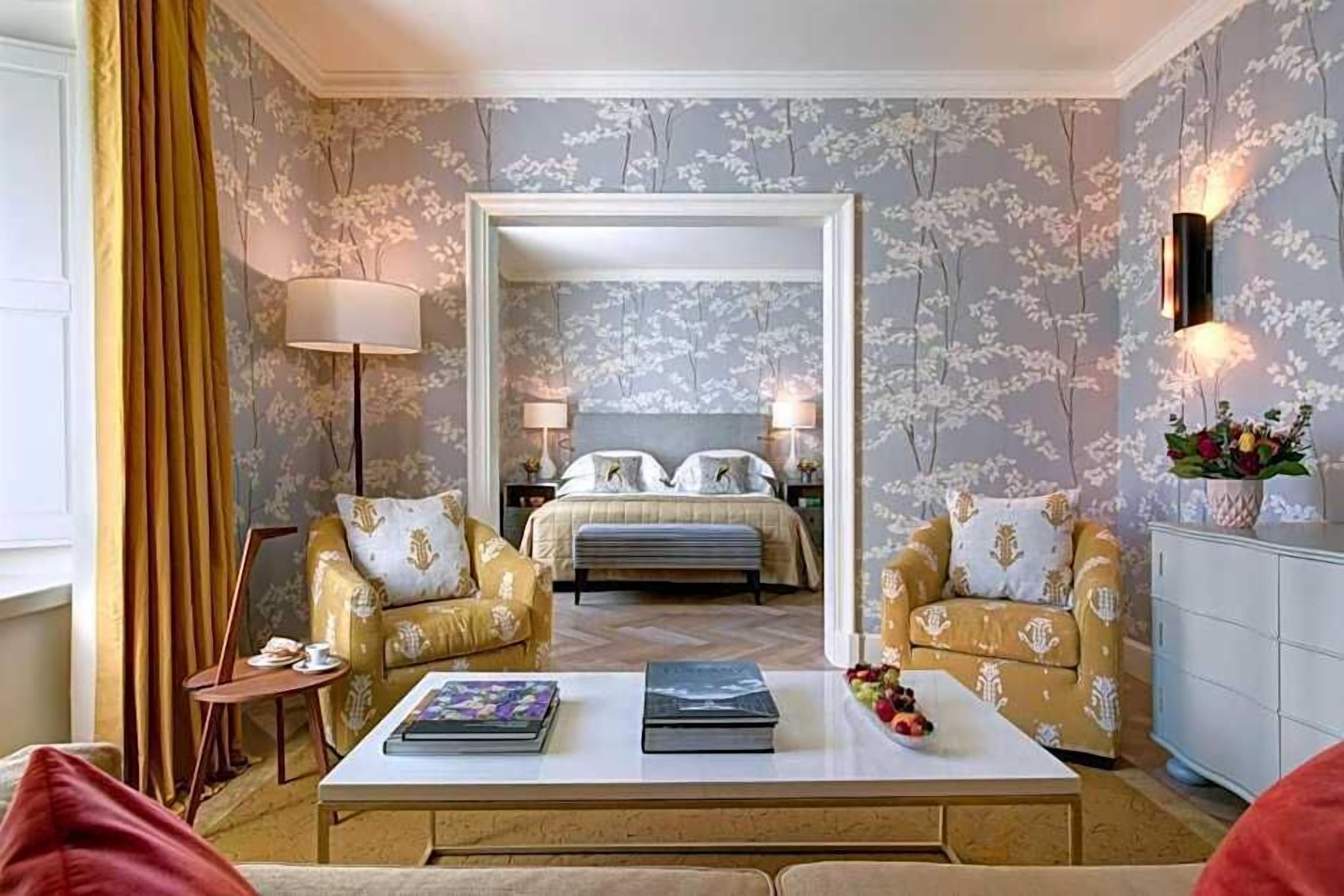 A hotel room with a bed, two sofas, a coffee table, a lamp, and a mirror.