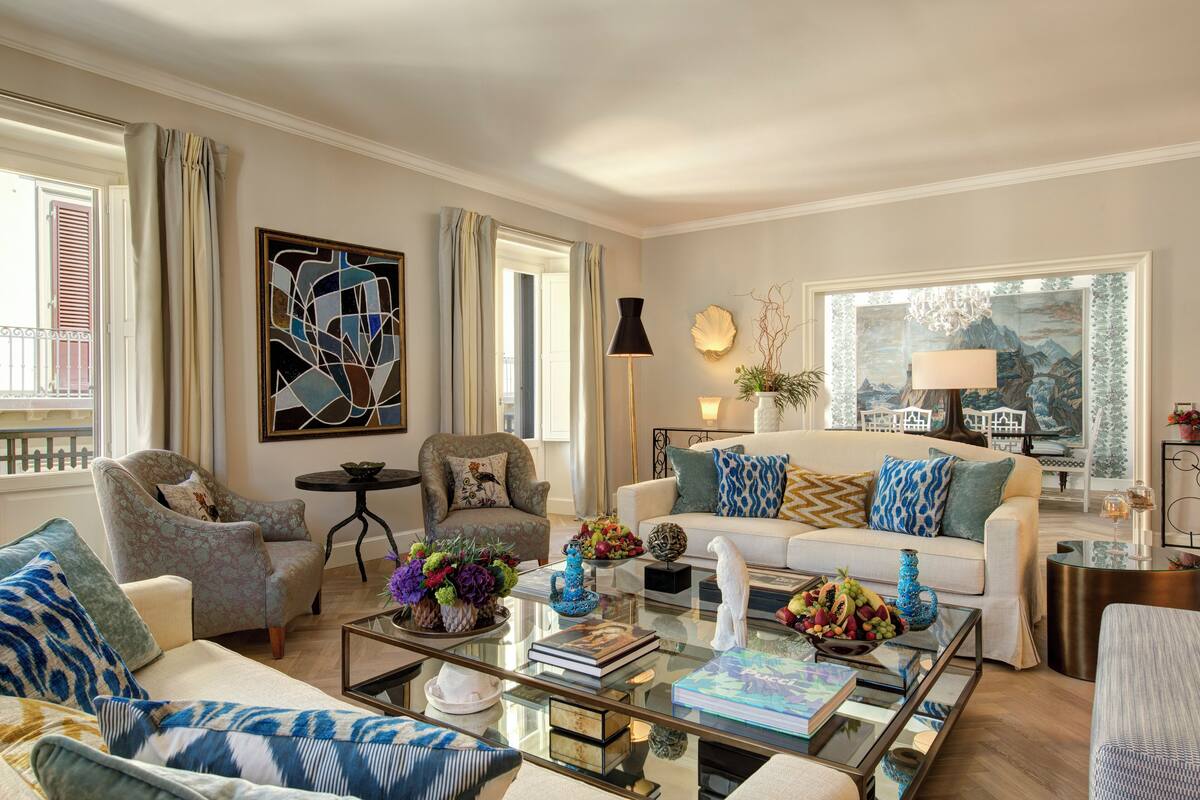 A well-lit living room with a sofa, armchairs, a coffee table, and a painting on the wall.