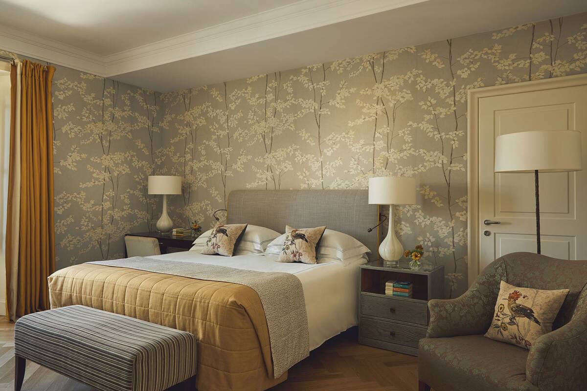 A bedroom with a bed, nightstands, a chair, and a door.