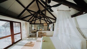 Una habitación amplia con una cama grande, un ventilador de techo y vistas al exterior.