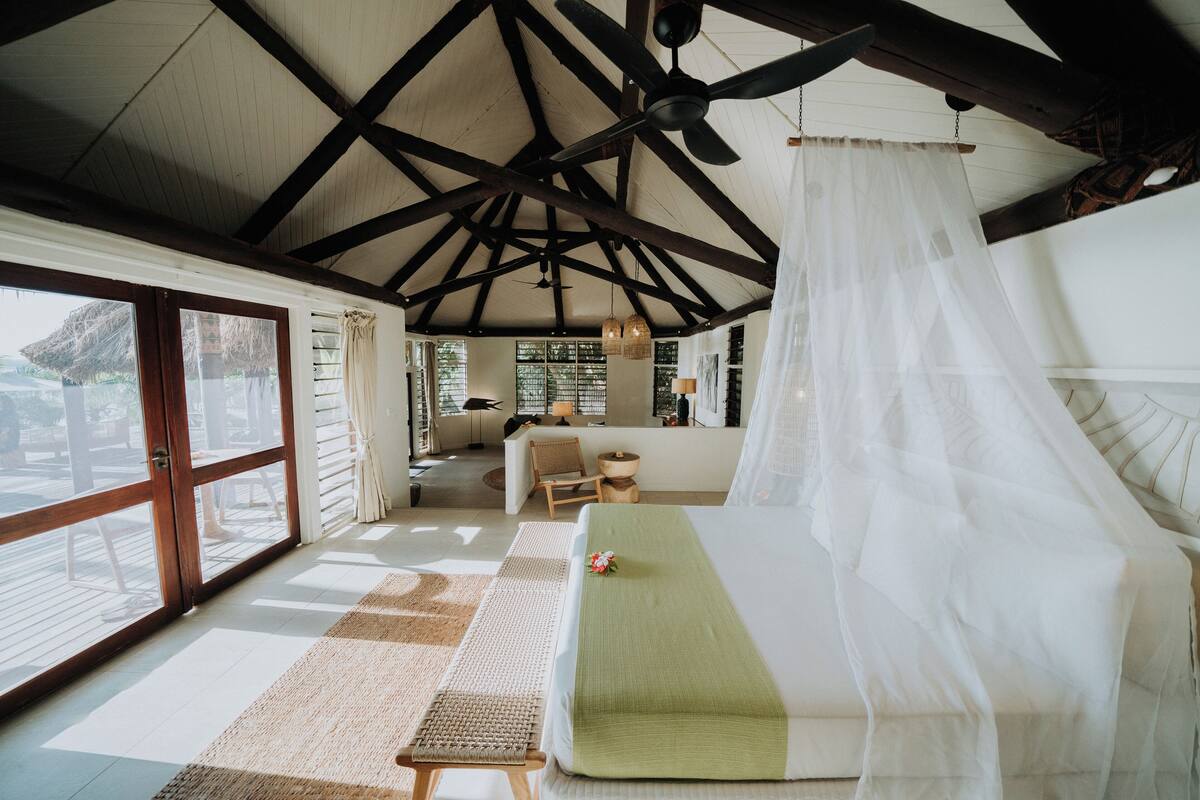 A spacious room with a large bed, a ceiling fan, and a view of the outdoors.