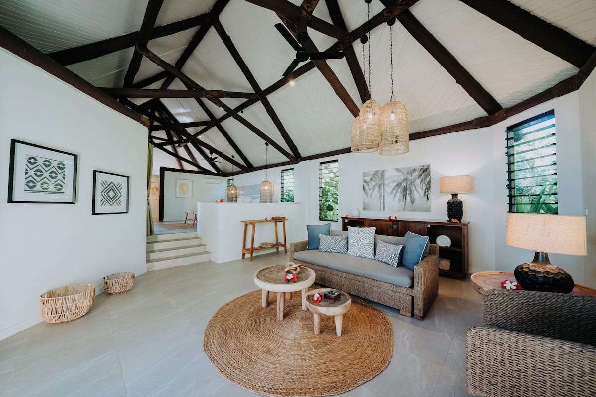A spacious living area with a high ceiling, a sofa set, a coffee table, and wicker baskets.