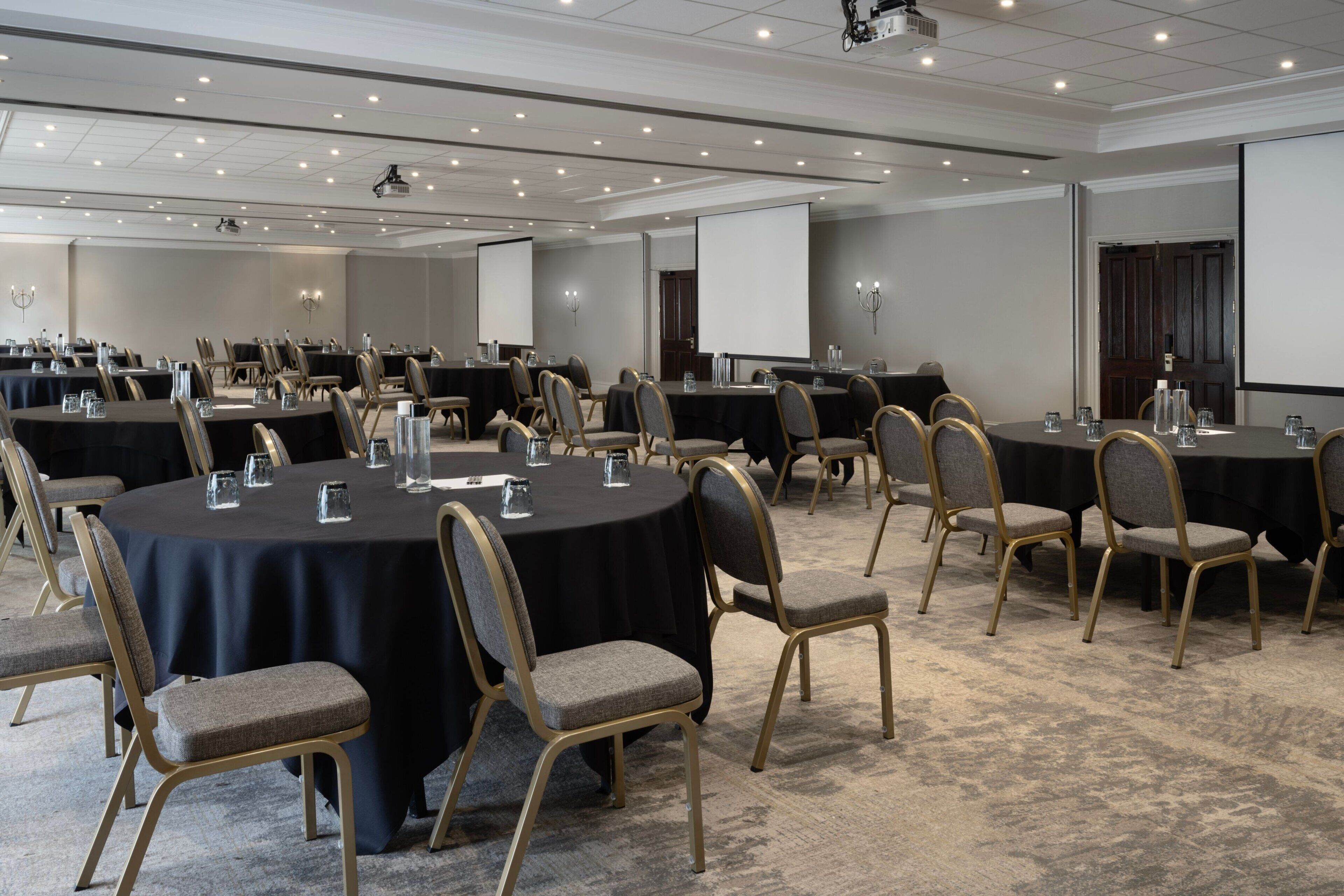 A conference room with multiple round tables, each with chairs and water glasses.