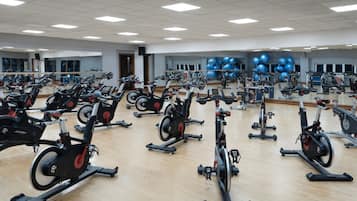 A gym with multiple stationary bikes, mirrors, and exercise balls.