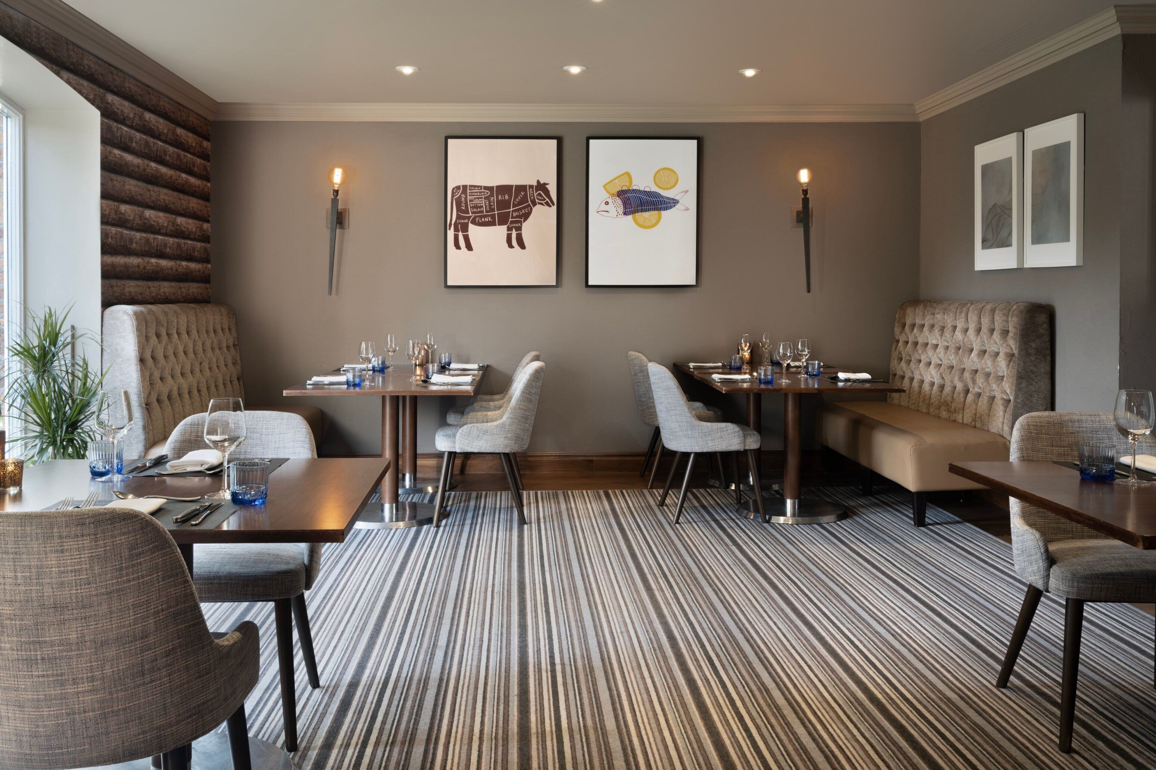 A modern dining area with striped carpet, cushioned seating, and wall-mounted artwork.
