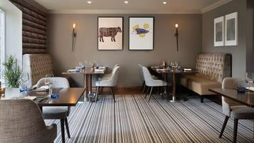 A modern dining area with striped carpet, cushioned seating, and wall-mounted artwork.