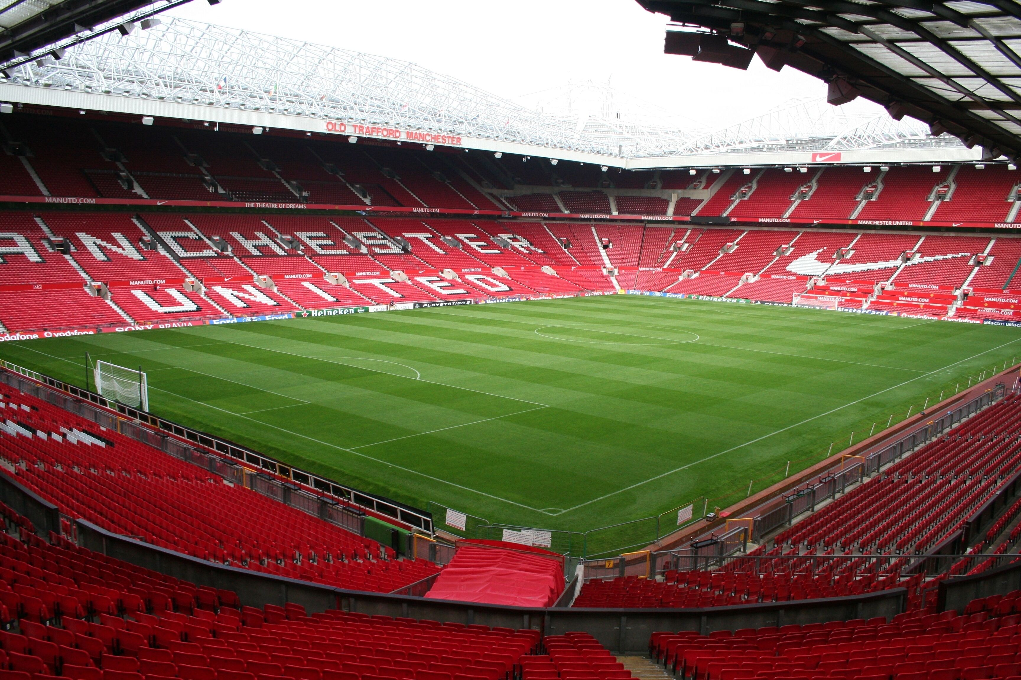 A stadium with red seating and a green field.