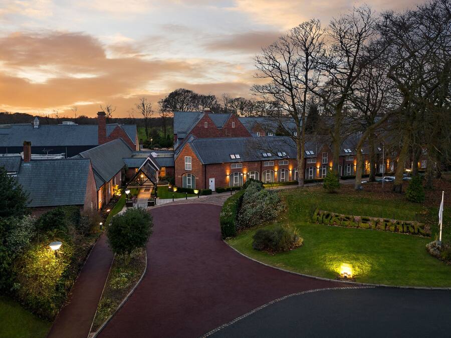A residential area with a paved driveway leading to a row of brick houses with sloped roofs.