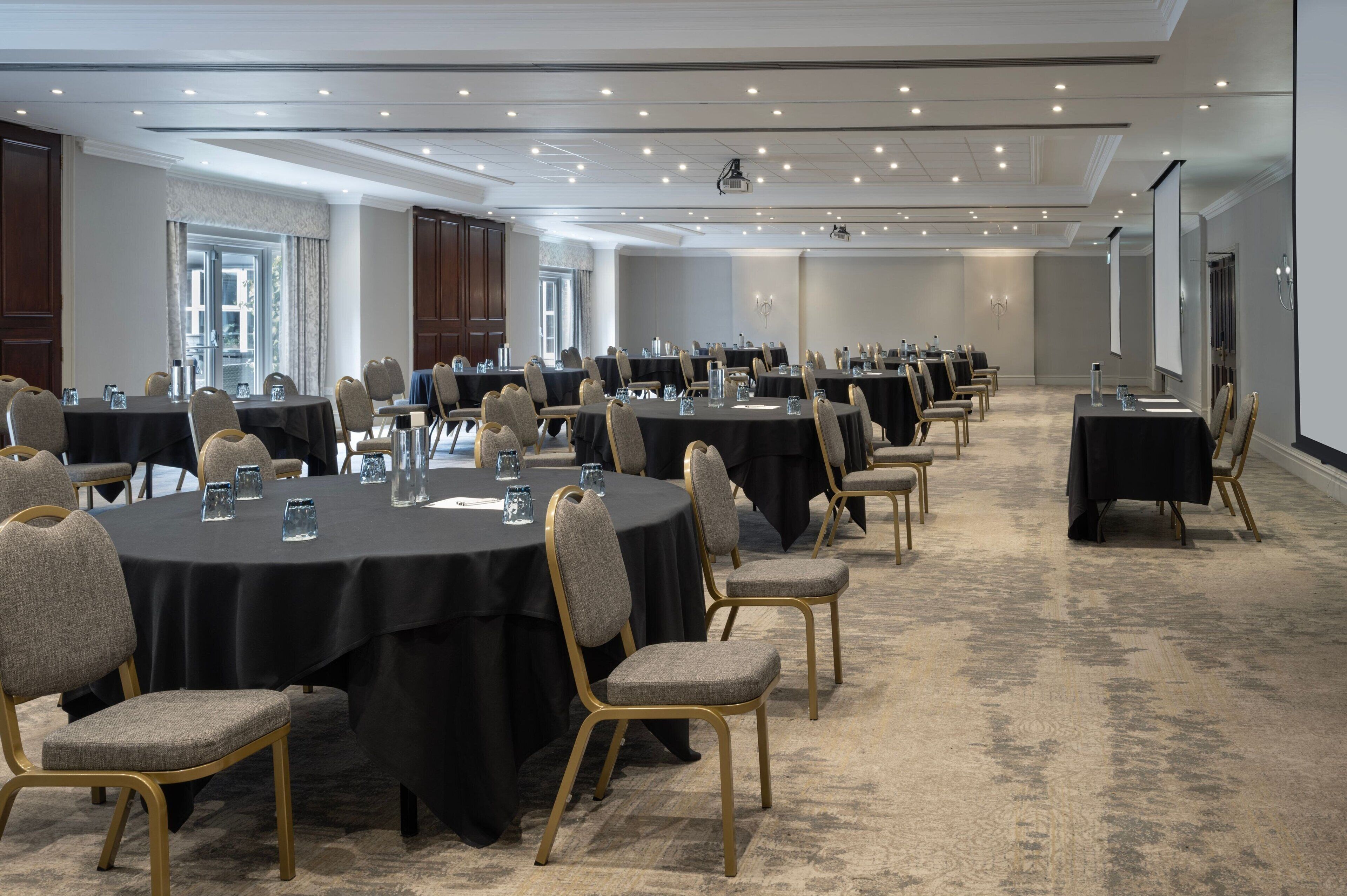 A conference room with multiple round tables, each with chairs and water glasses.