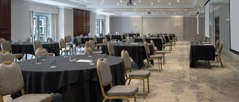 A conference room with multiple round tables, each with chairs and water glasses.