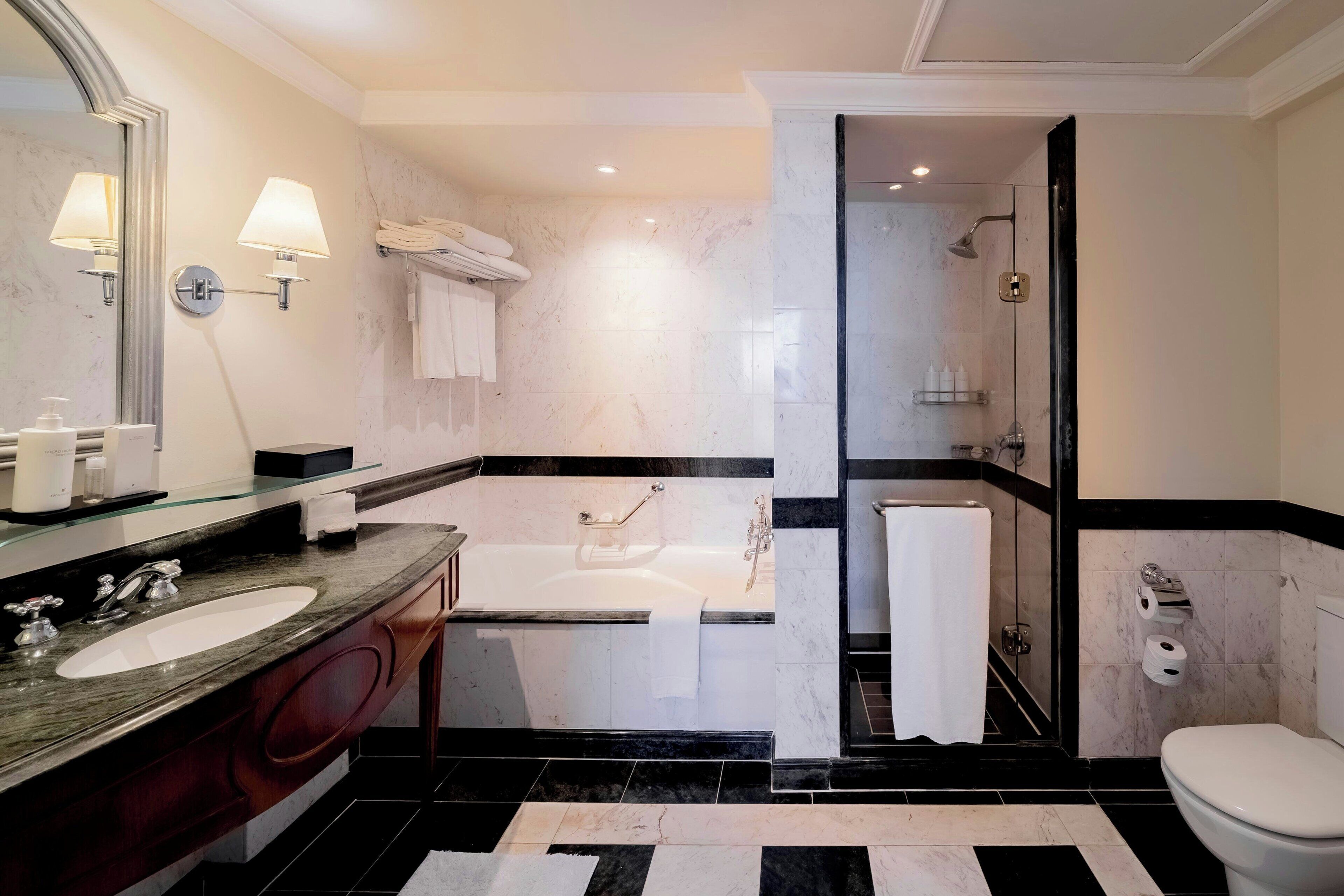 A modern bathroom with a large sink, two mirrors, a bathtub, and a shower area.