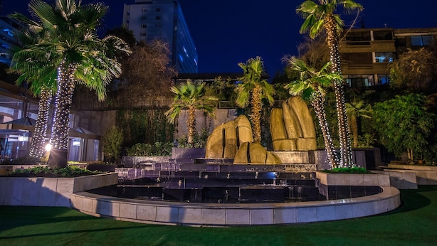 A nighttime outdoor area with a fountain, palm trees, and a building in the background. - Santiago Marriott Hotel (Santiago)
