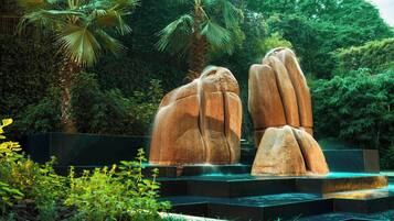 Un jardín de esculturas con grandes esculturas de piedra y un elemento acuático.