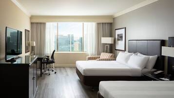 Une chambre d’hôtel avec deux lits, un bureau, une chaise, une télévision et une fenêtre donnant sur la ville.