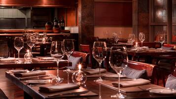 Un restaurante con varias mesas dispuestas para comer, cada una con copas de vino y servilletas.