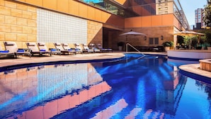 A modern hotel with a large indoor pool, sun loungers, and a view of the cityscape. - Santiago Marriott Hotel (Santiago)