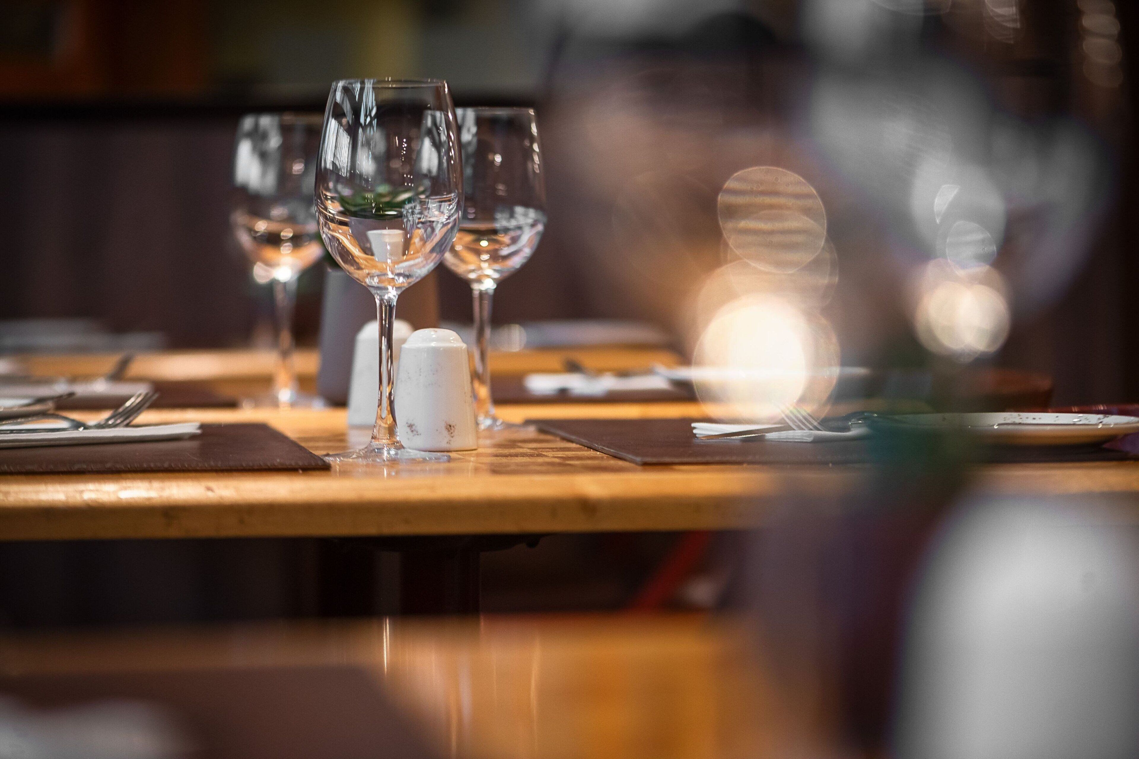 A dining table with multiple wine glasses and a salt shaker.