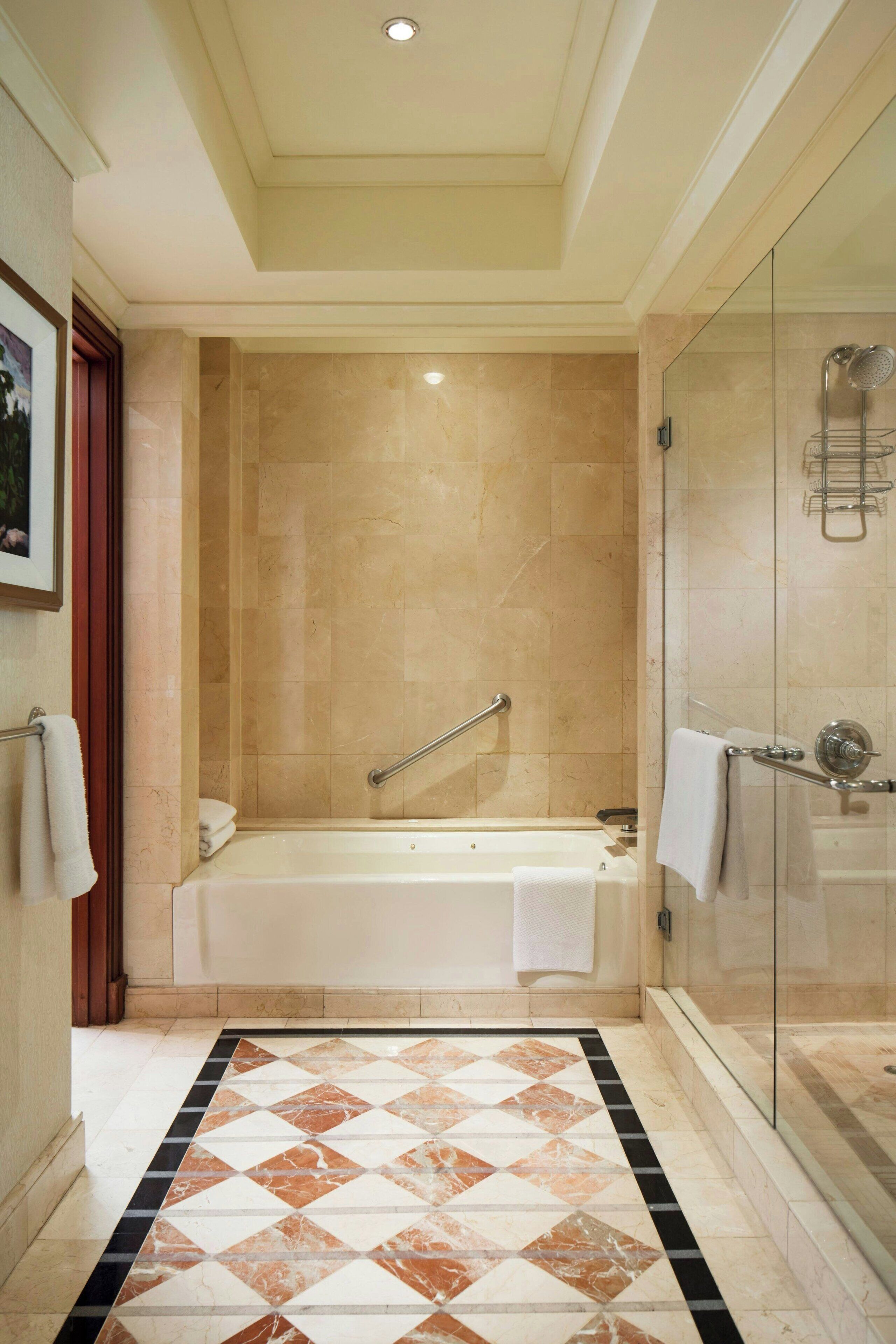 Une salle de bain avec une baignoire, une cabine de douche en verre et un carrelage au sol.