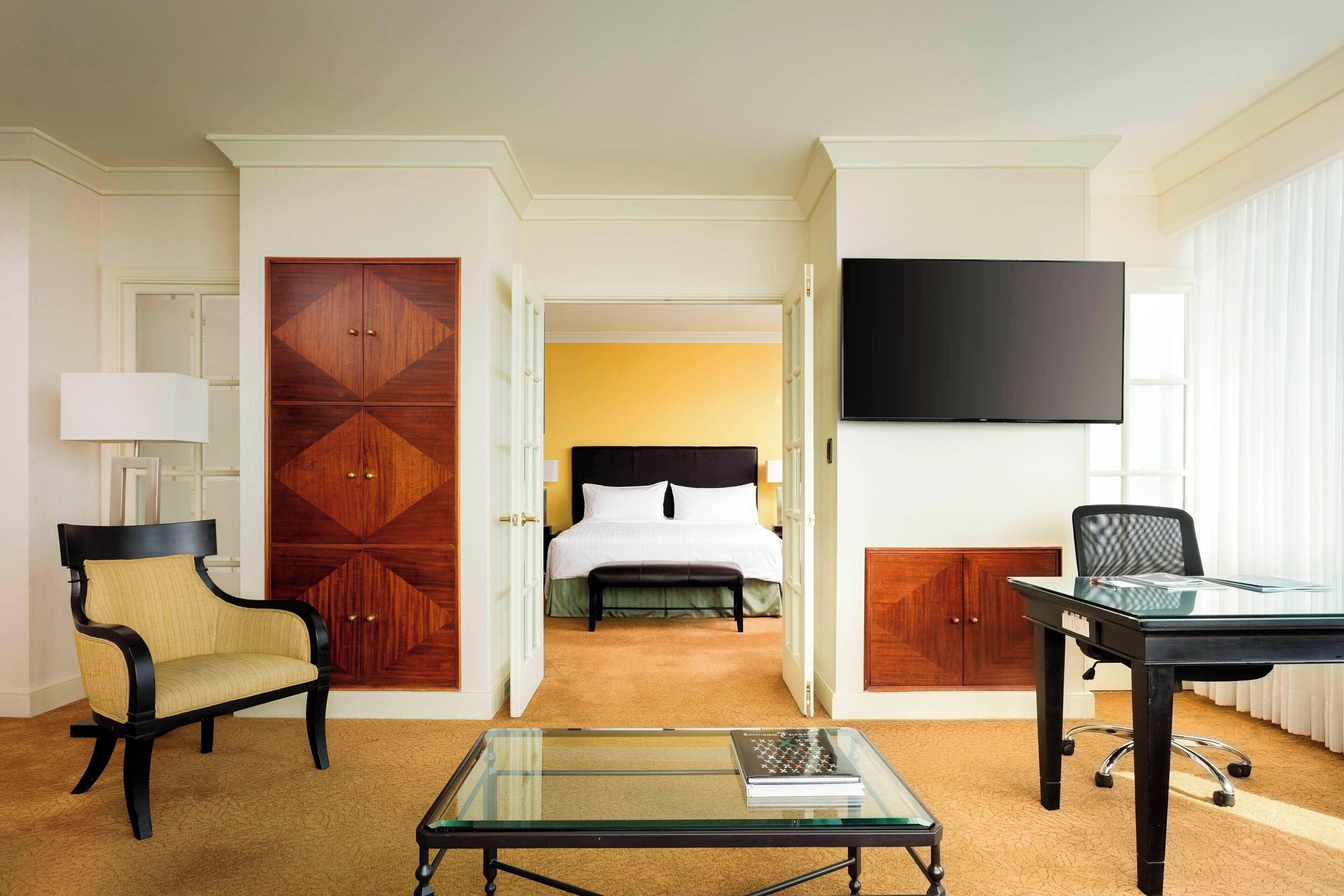 Ein Hotelzimmer mit Bett, Fernseher, Schreibtisch und Stuhl.