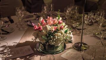 Una mesa dispuesta para un evento formal, con un centro de flores, copas de vino vacías y menús.