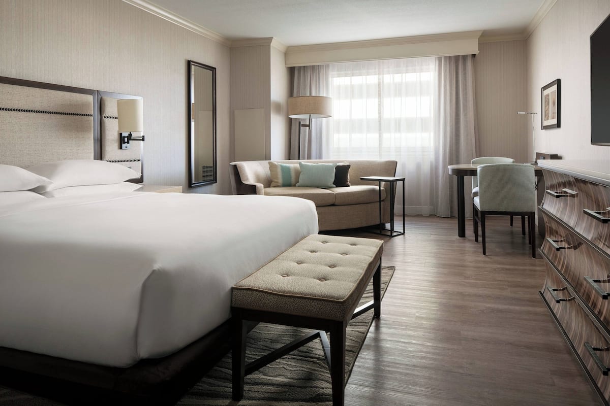 A hotel room with a large bed, a sofa, a desk, and a dresser.