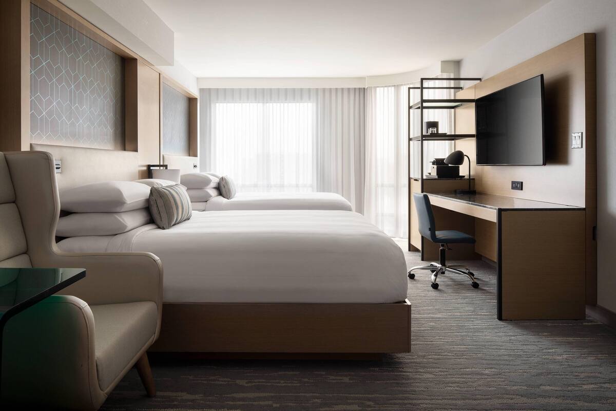 Una habitación de hotel moderna con una cama grande, un escritorio, una silla y un televisor.