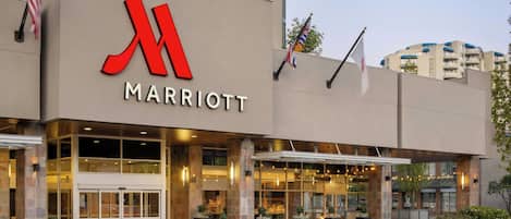 A Marriott hotel entrance with a large red 'M' logo, glass doors, and outdoor seating area.