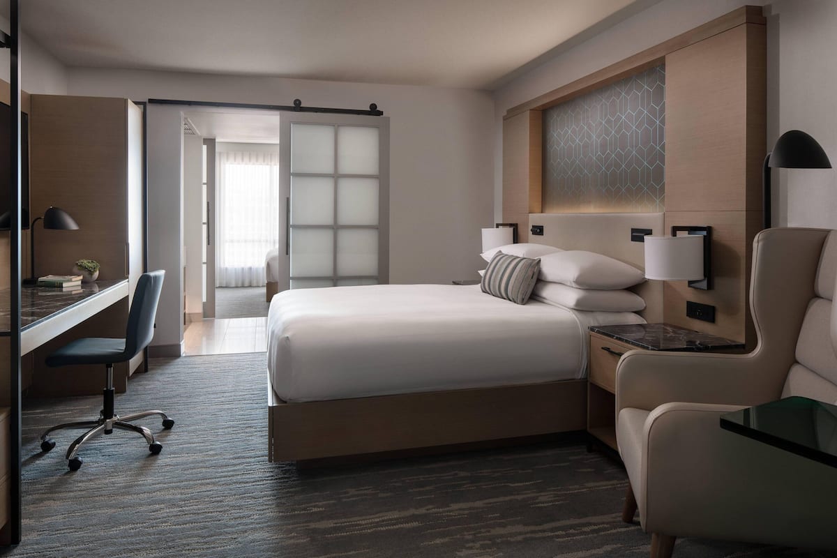 Una habitación de hotel con una cama grande, un escritorio, una silla y una mesita de noche.