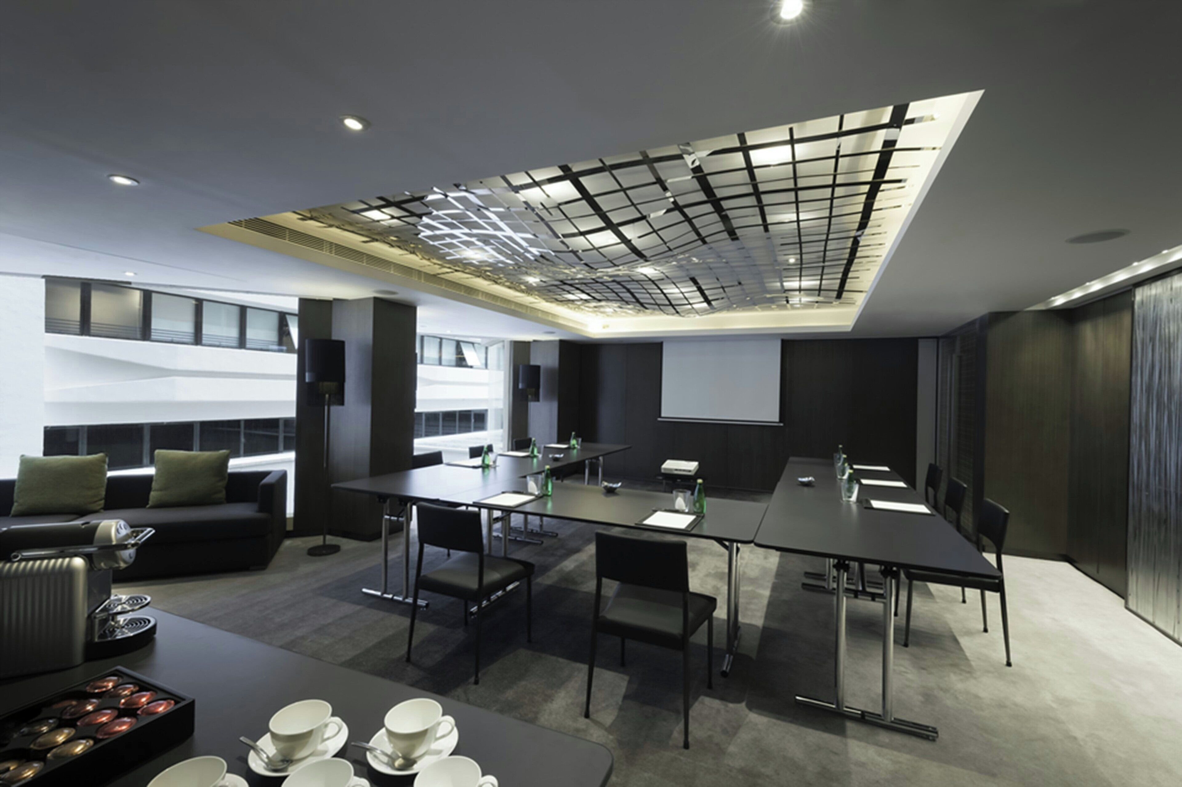A modern conference room with a high ceiling, a large table, and a projector screen.