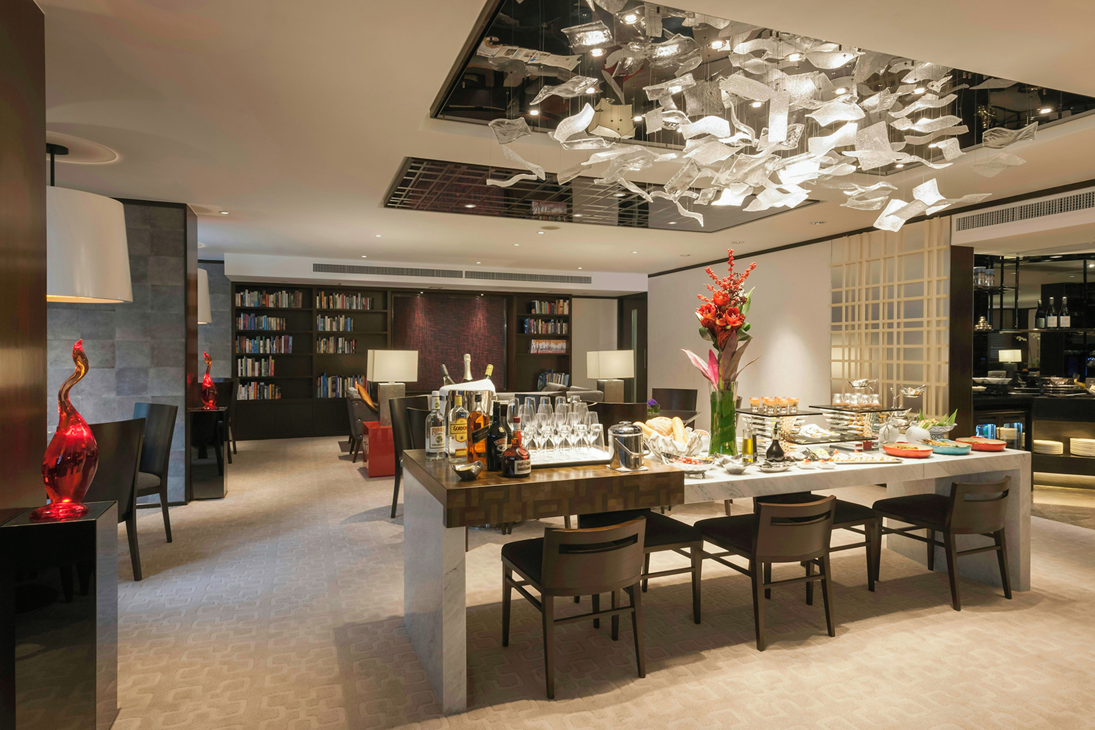 Interior moderno com área de jantar, estantes de livros e teto decorativo.