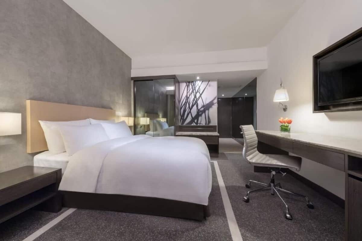Une chambre d’hôtel équipée d’un lit, d’un bureau, d’une chaise, d’une télévision et offrant une vue sur un escalier.
