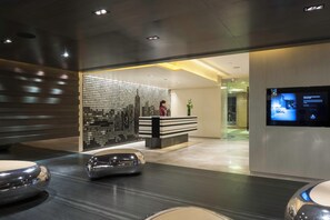 A modern reception area with a glass partition, a reception desk, and a digital display. - Gateway, Marco Polo Hotel (Kowloon)