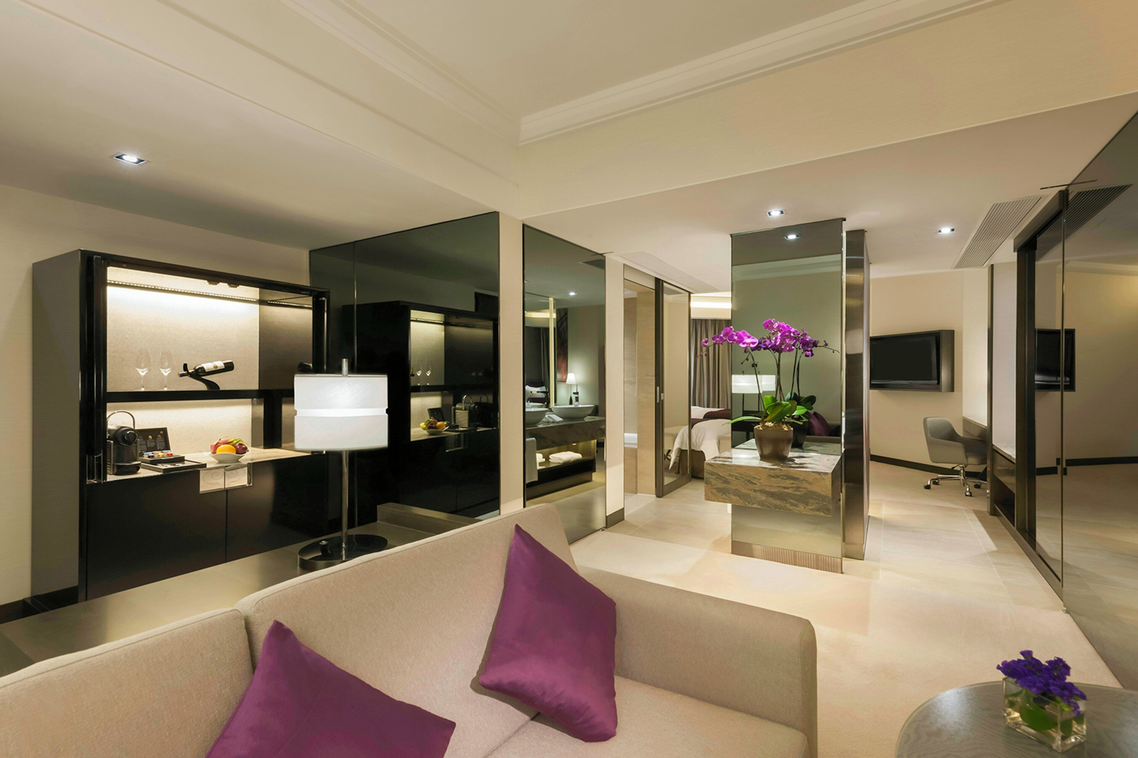 A modern hotel room with a living area, a kitchen, and a bathroom.