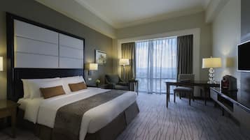 A hotel room with a large bed, a desk, a chair, a TV, and a view of the outdoors.