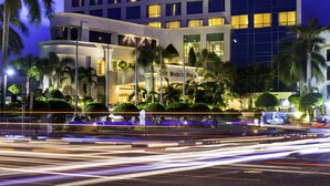 A high-rise hotel with multiple floors, illuminated windows, and a well-lit entrance area with palm trees. - Marco Polo Davao (Davao)