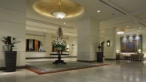 A spacious lobby with a central floral arrangement, a seating area, and a large decorative wall. - Marco Polo Davao (Davao)